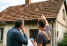 Tetőfedő szakember és háztulajdonos vizsgál egy rossz állapotú családi ház tetőjét tetőfelújítás előtt